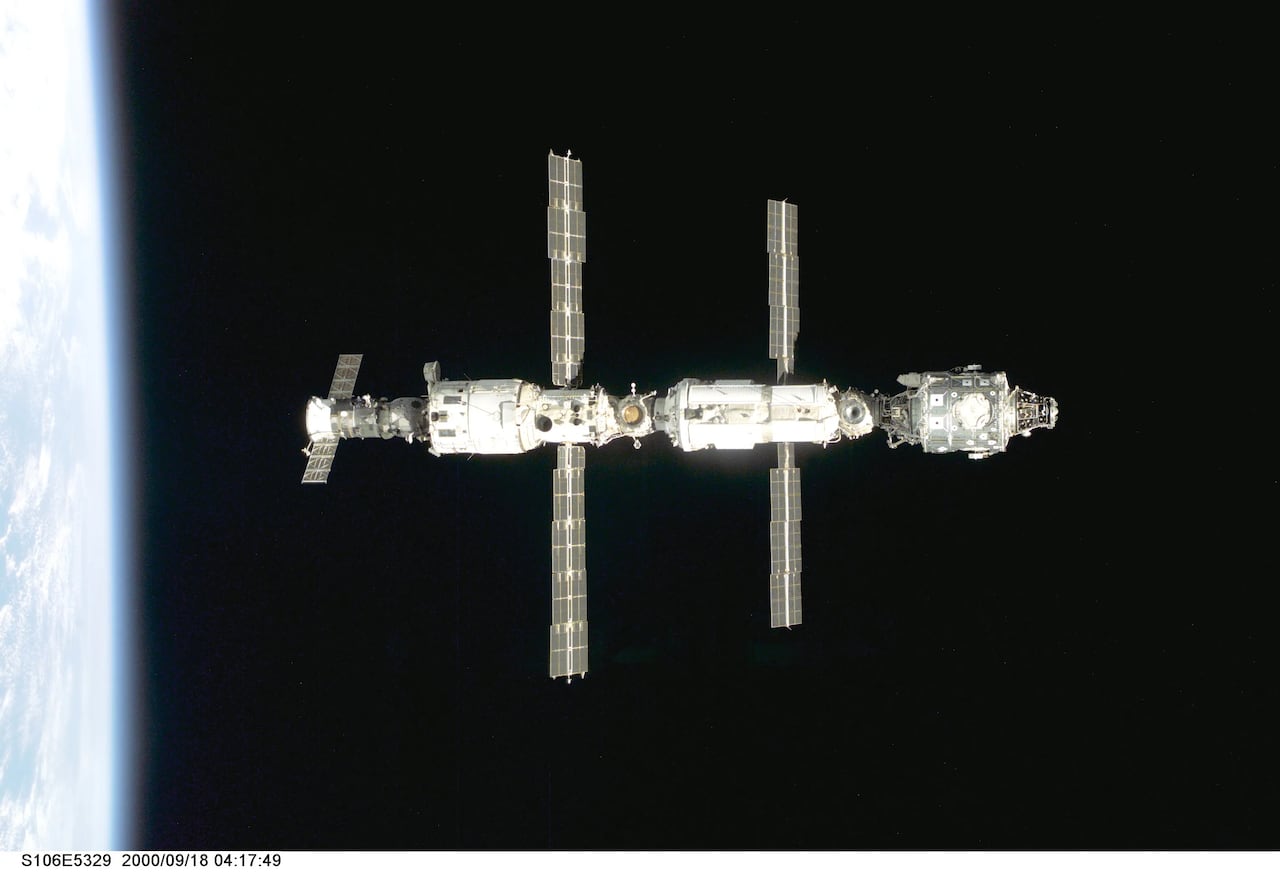 A space station with four solar panels is seen hanging in the blackness of space.