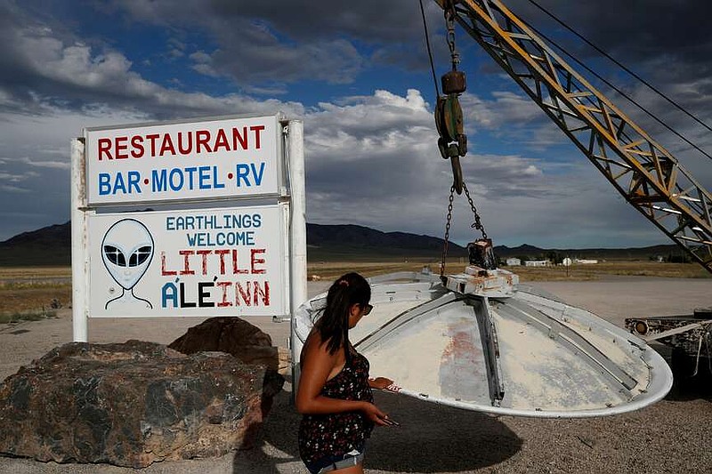 FILE - A woman looks at a UFO display outside of the Little A'Le'Inn, in Rachel, Nev., the closest town to Area 51, July 22, 2019. (AP Photo/John Locher, File)