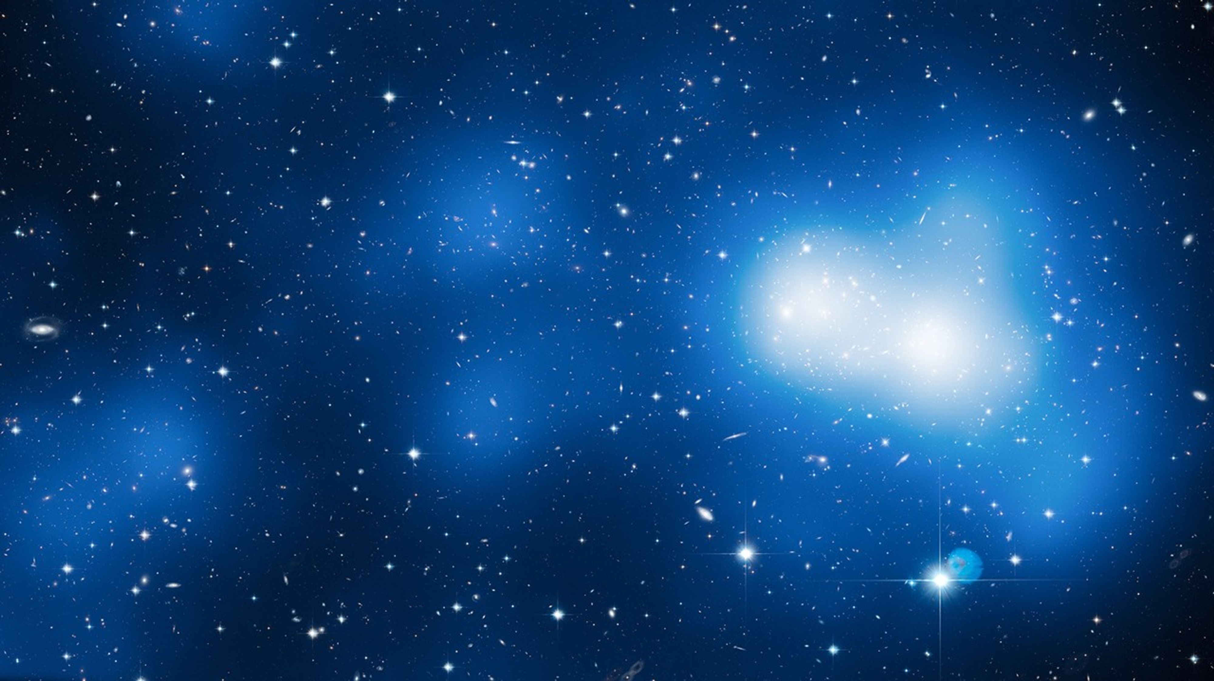 Black background dotted with galaxies and a few foreground stars. Bright-blue and white areas indicate where mass is concentrated.