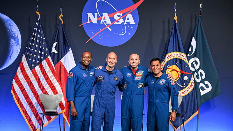 Andre Douglas, Luca Parmitano, Randy Bresnik and Frank Rubio pose in front of flags