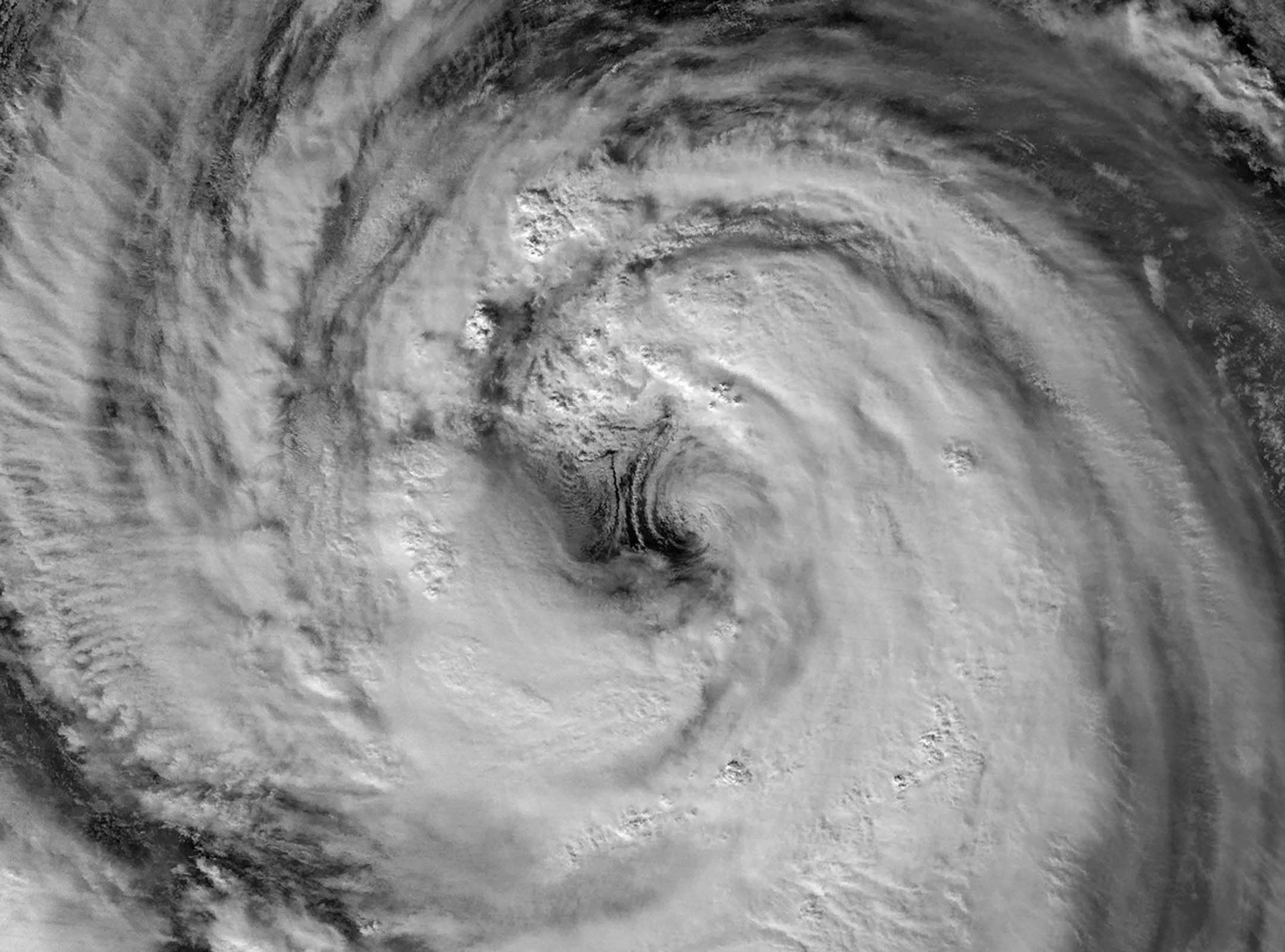 A nighttime satellite image highlights the structure of a typhoon’s large eye and surrounding eyewall.
