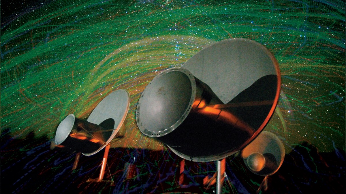 closeup photo of two silver radio dishes, with green swirls in a dark sky behind them